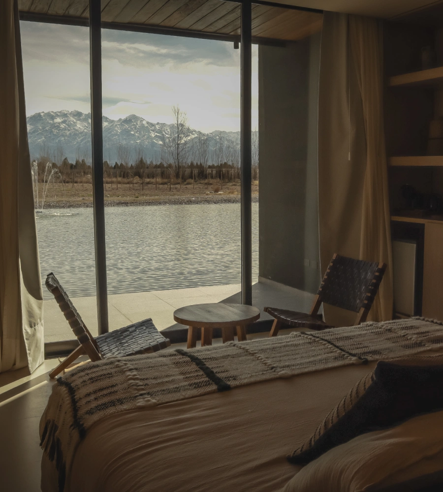Room with bed and view of the lake and mountains from a large window