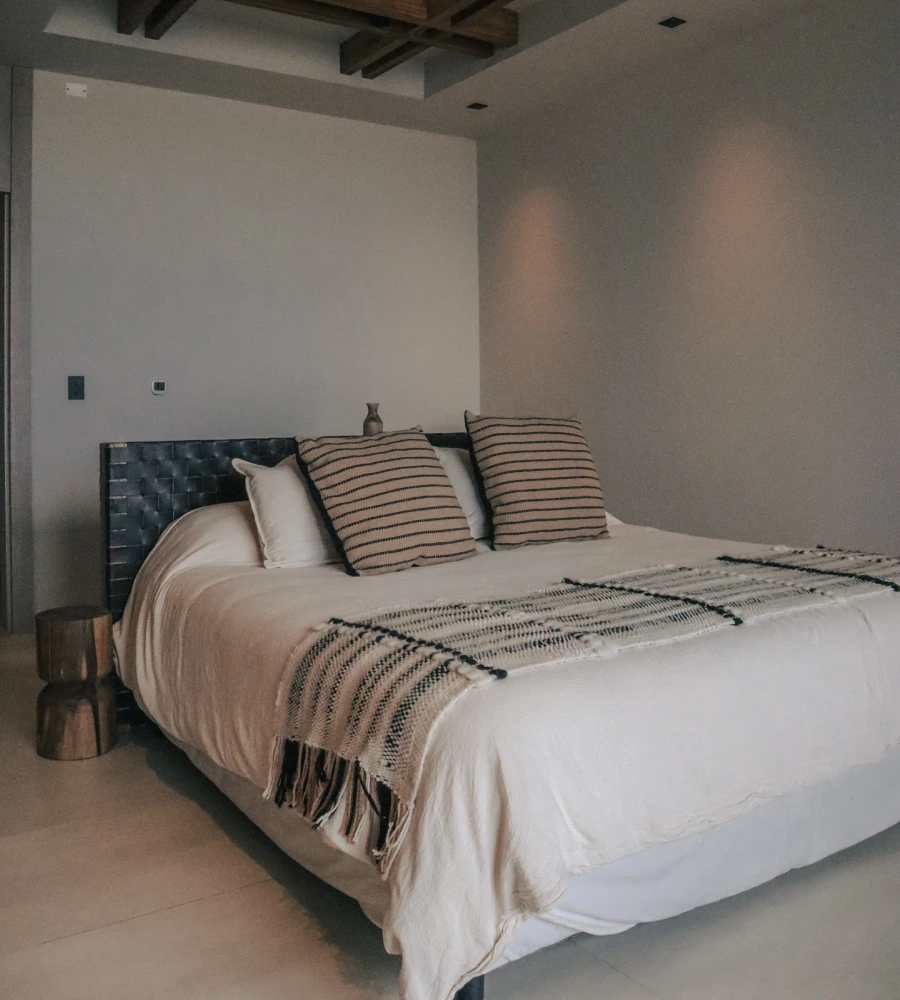 Bed with upholstered headboard and striped cushions in a minimalist bedroom