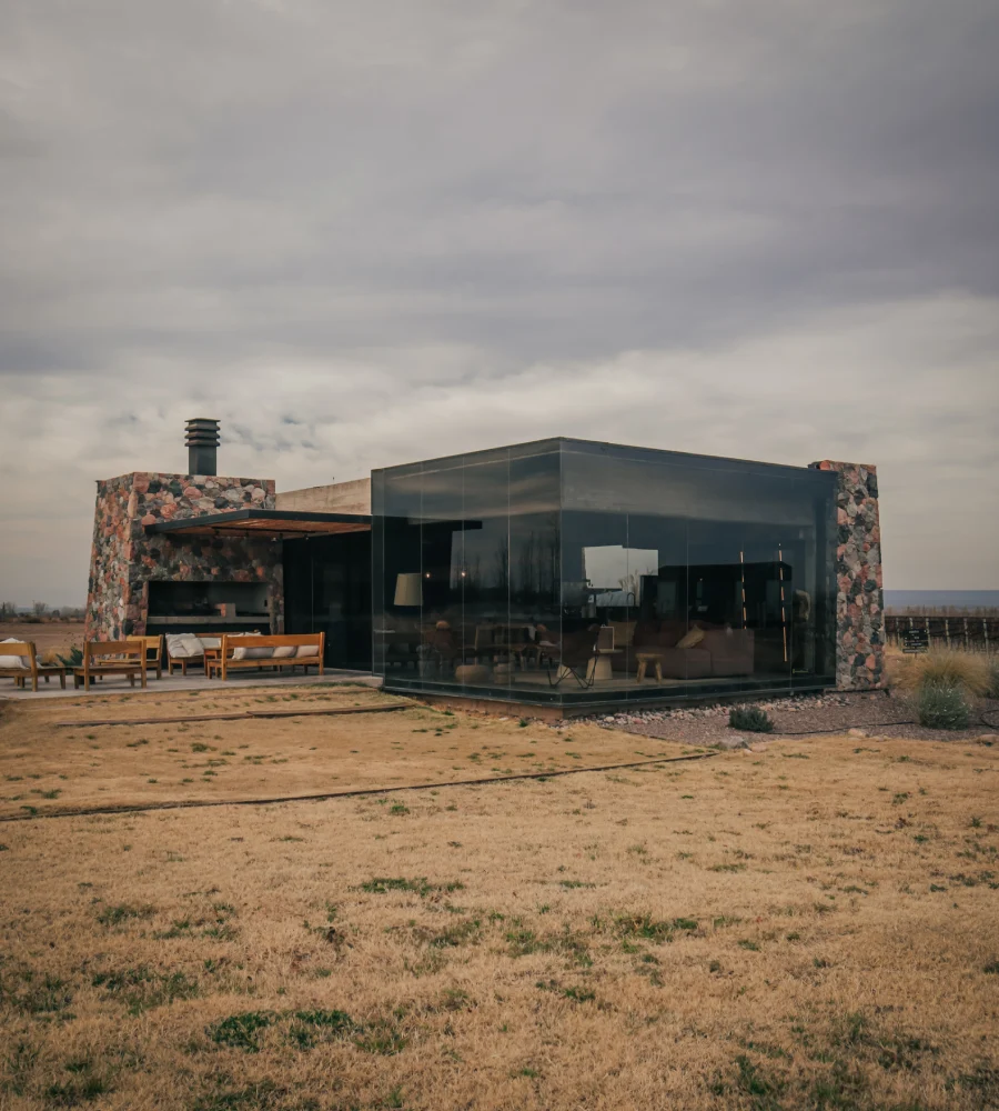 Modern glass house with fireplace and outdoor patio, cloudy sky